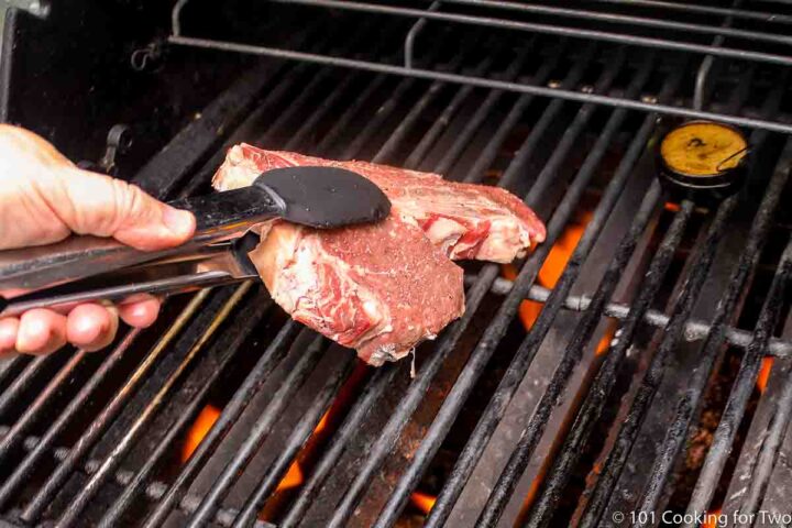placing porterhouse steak on a grill