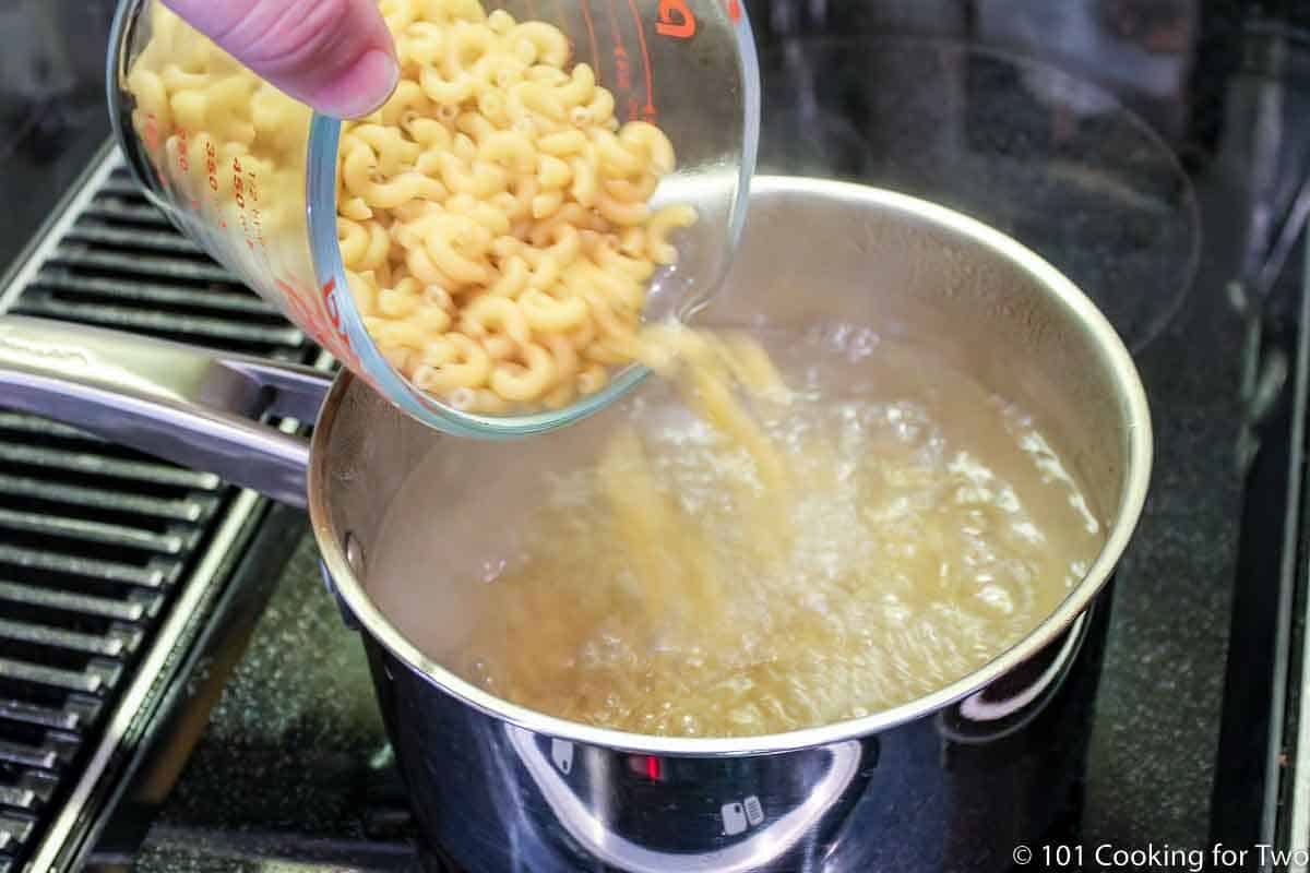 pouring dry pasta into boiling water.