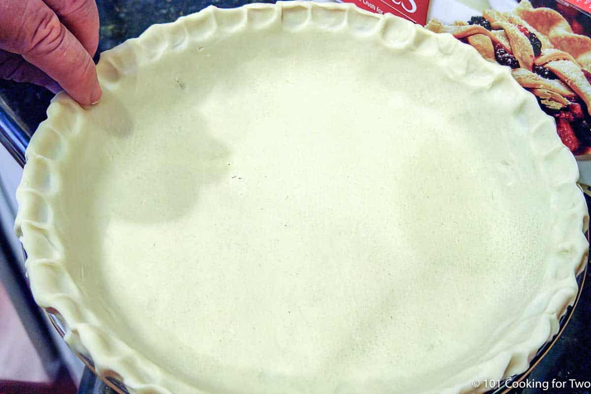 spreading a raw pie crust on pan.