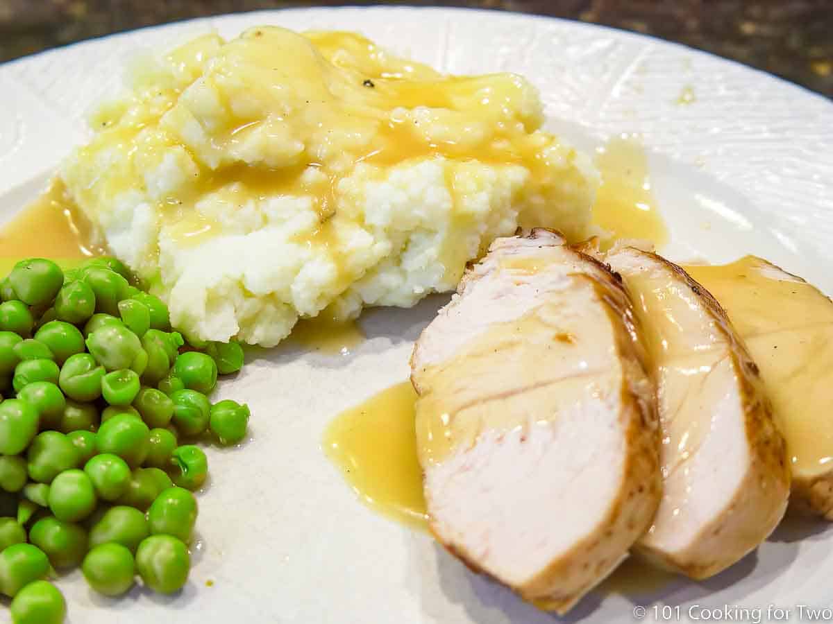 white plate with turkey slices and potatoes with gravy