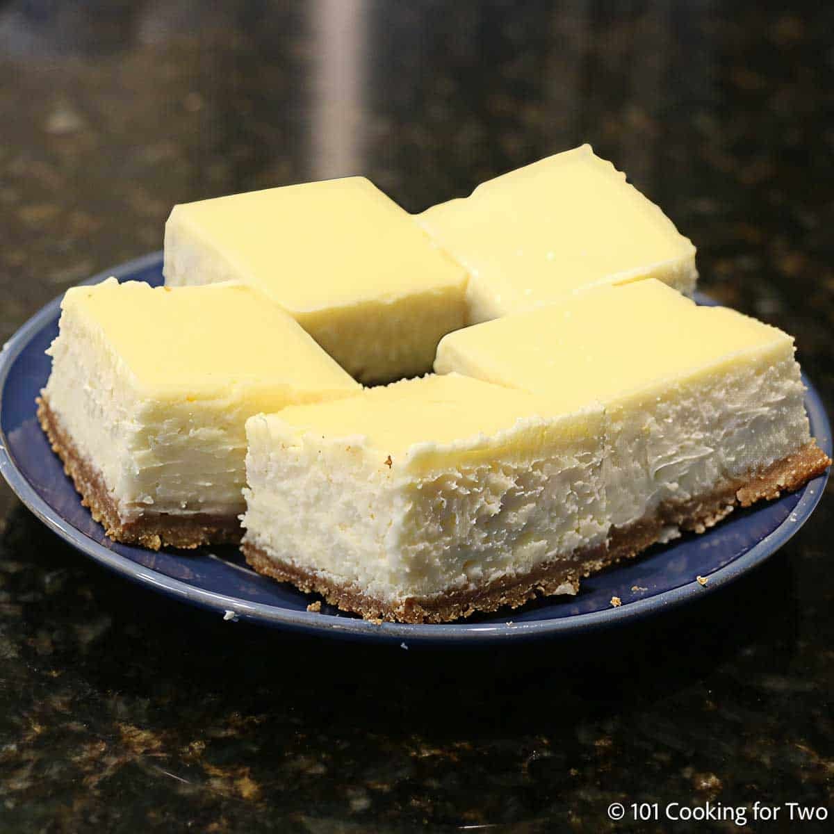 Cheesecake bars on a blue plate.