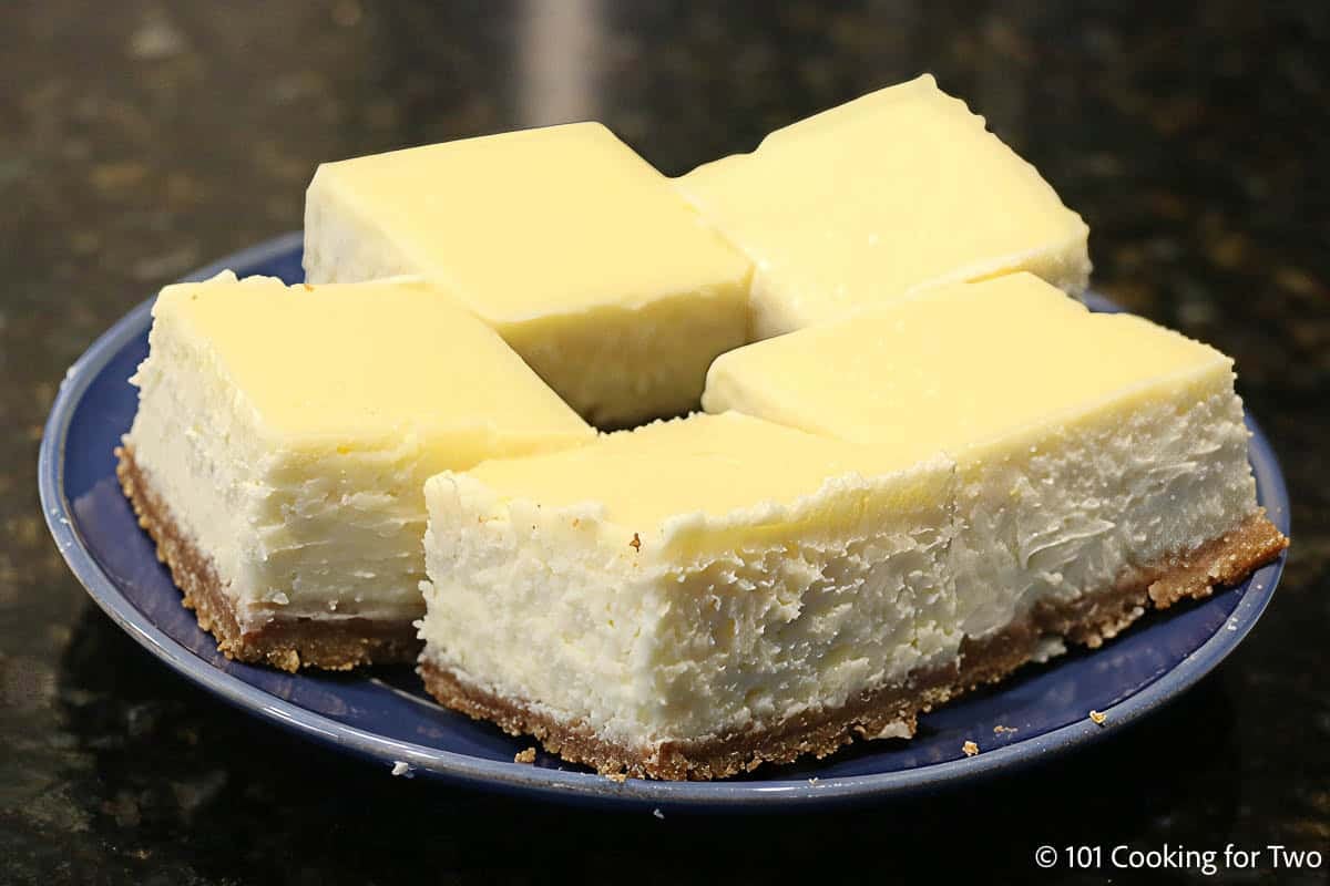 Cheesecake bars on blue plates.
