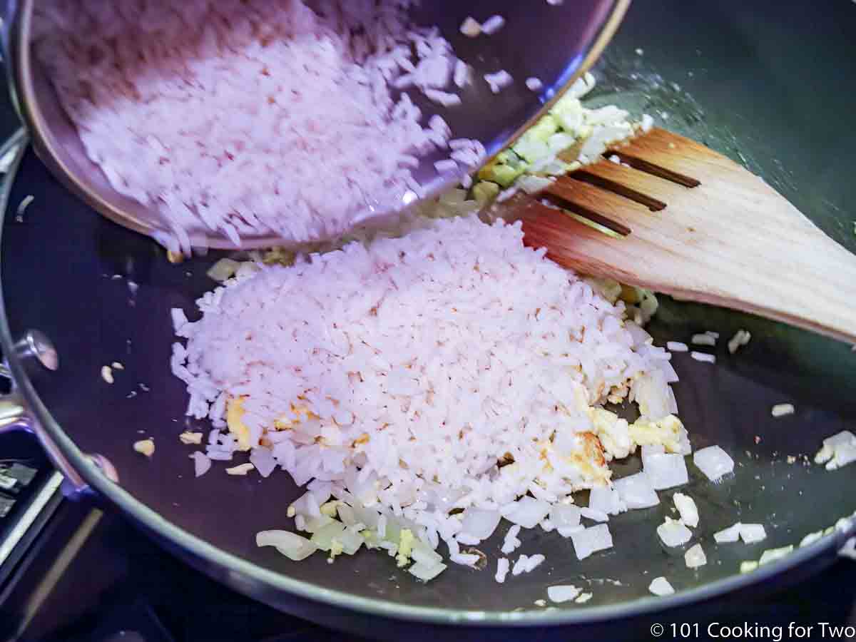 adding cooked rice to scrambled egg and onion.