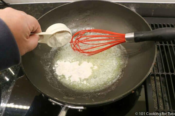 adding flour to melted butter to make a roux