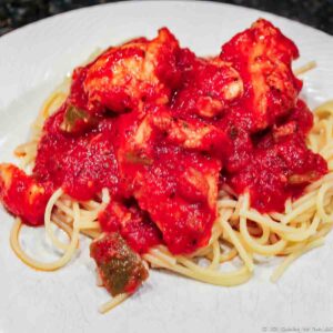 chicken cacciatore on pasta and on white plate