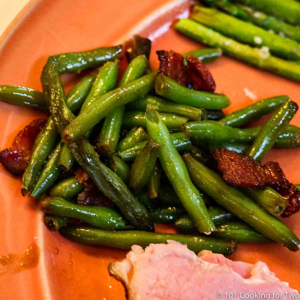green beans with bacon on an orange plate.