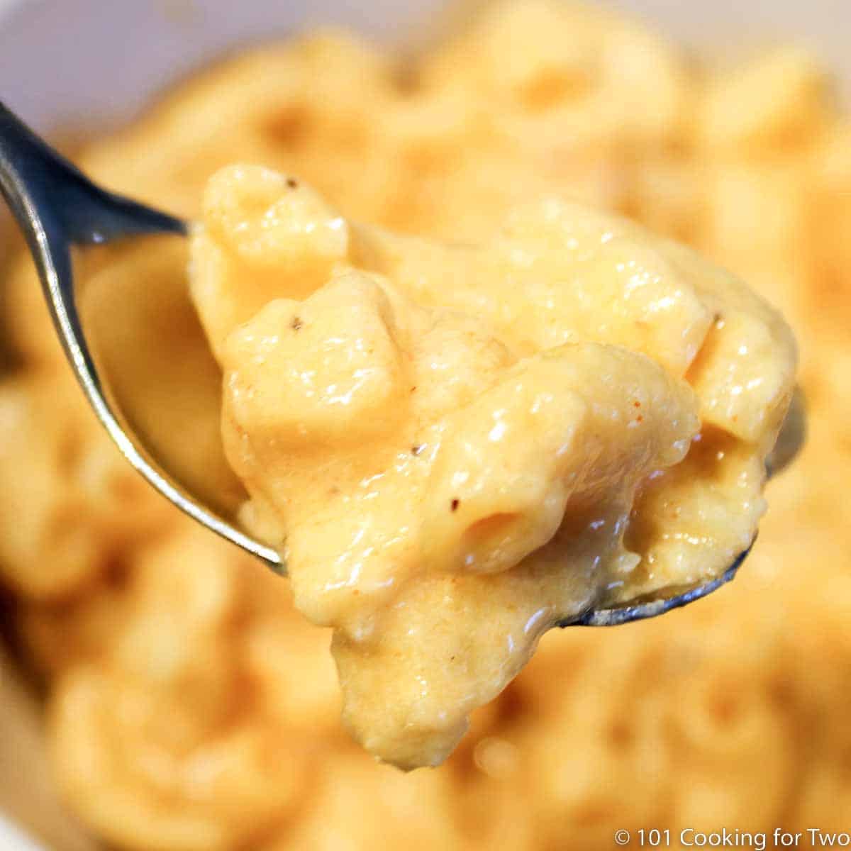mac and cheese on a spoon over a bowl.