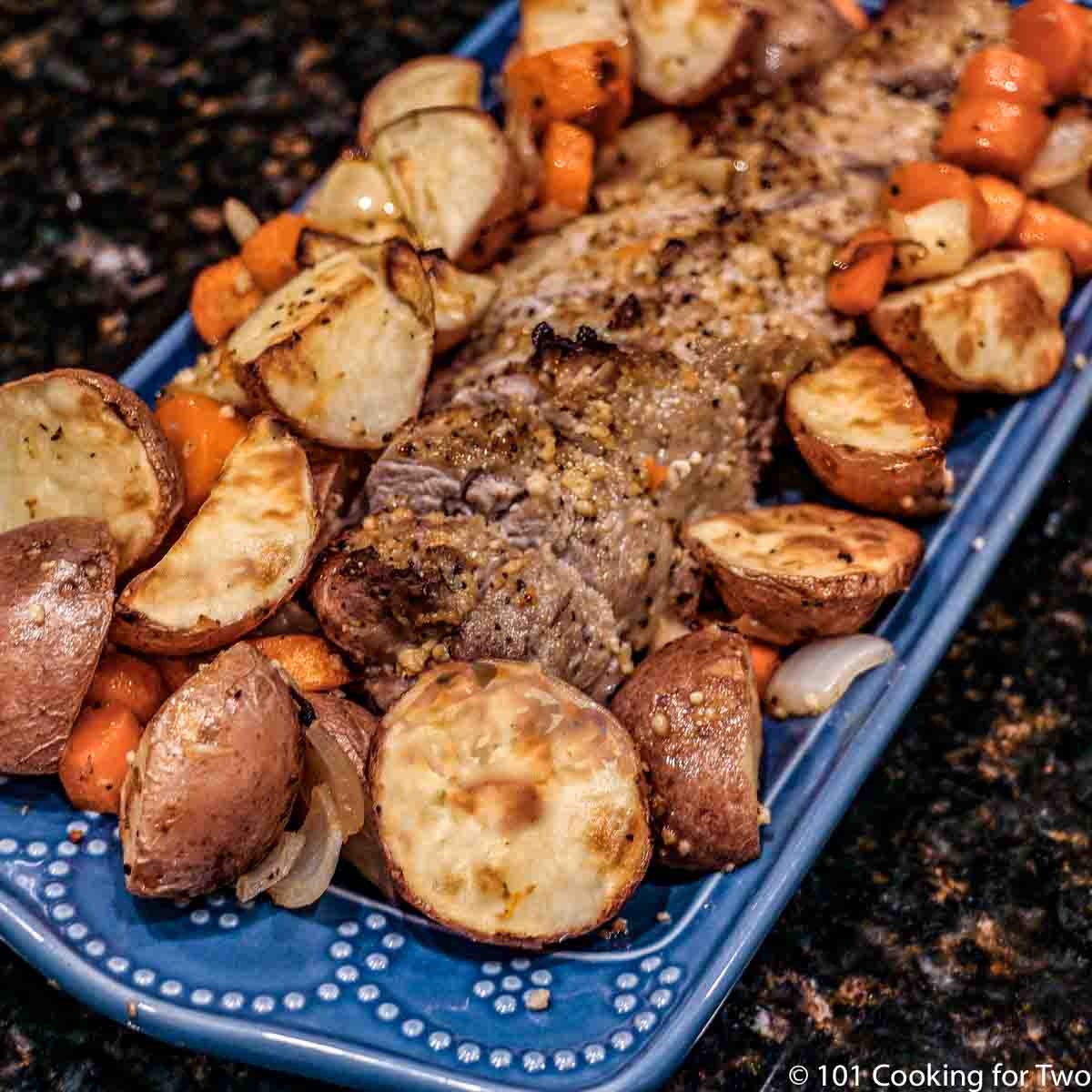 Sheet pan pork tenderloin on a serving dish with carrots and potatoes.