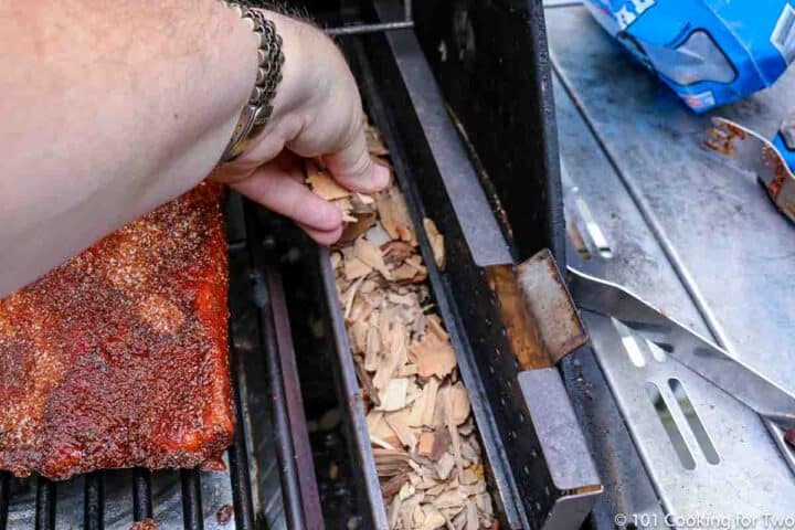 adding wood chips to smoking box