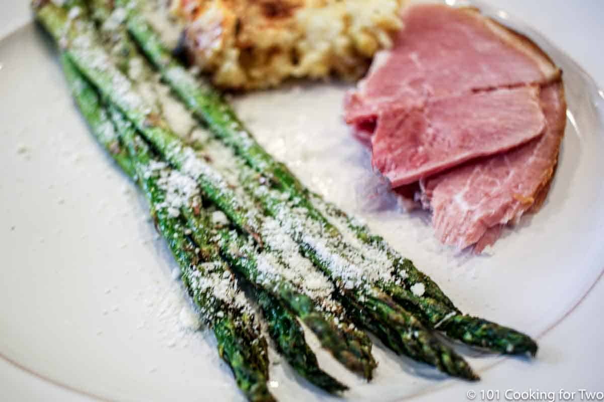 asparagus with Parmesan cheese on plate with ham.