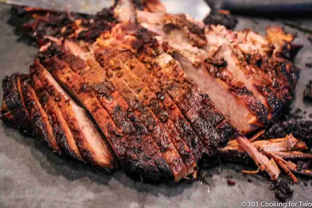 Cut brisket on a black board with knife.