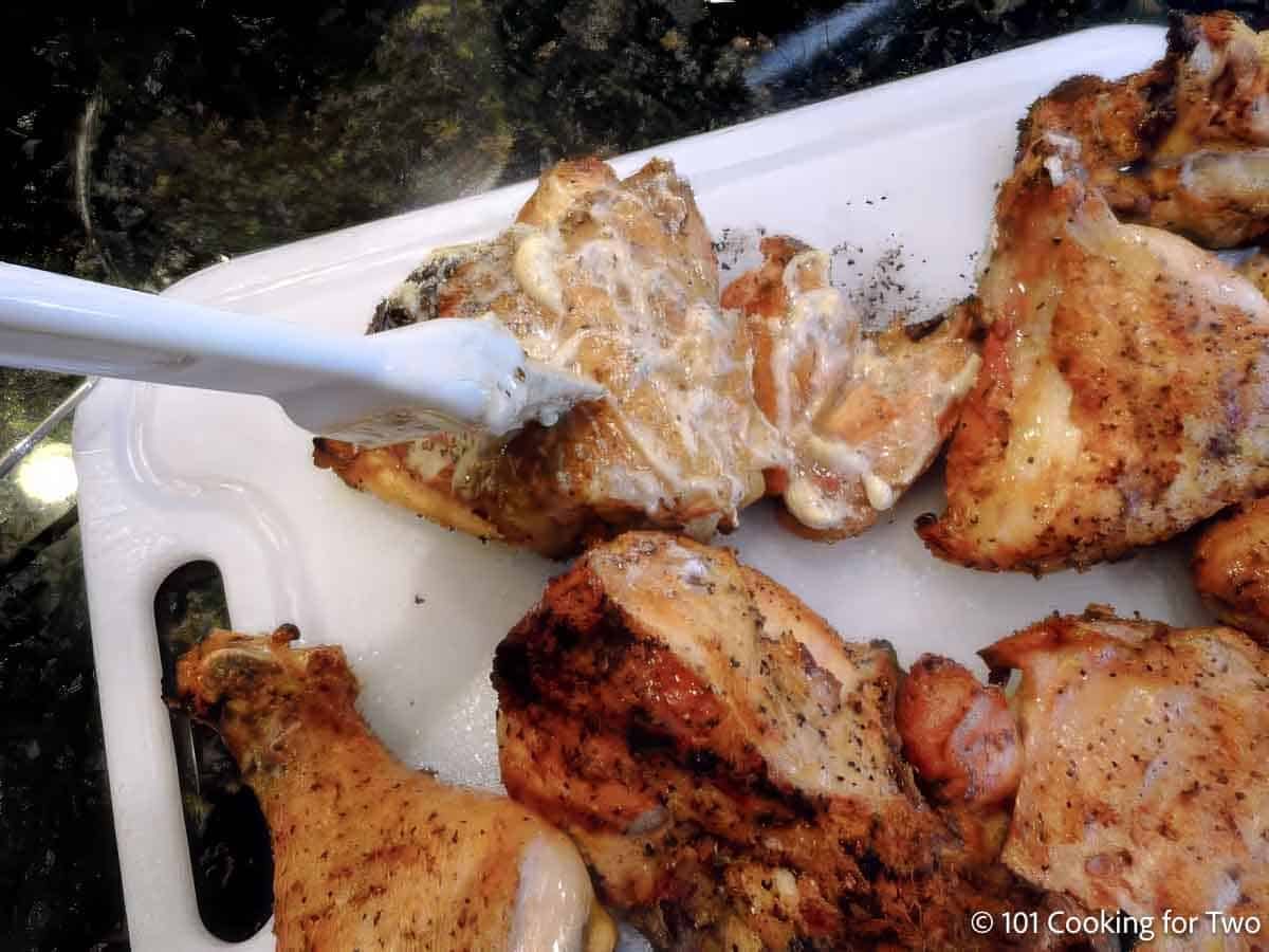 Brushing white BBQ sauce on chicken.