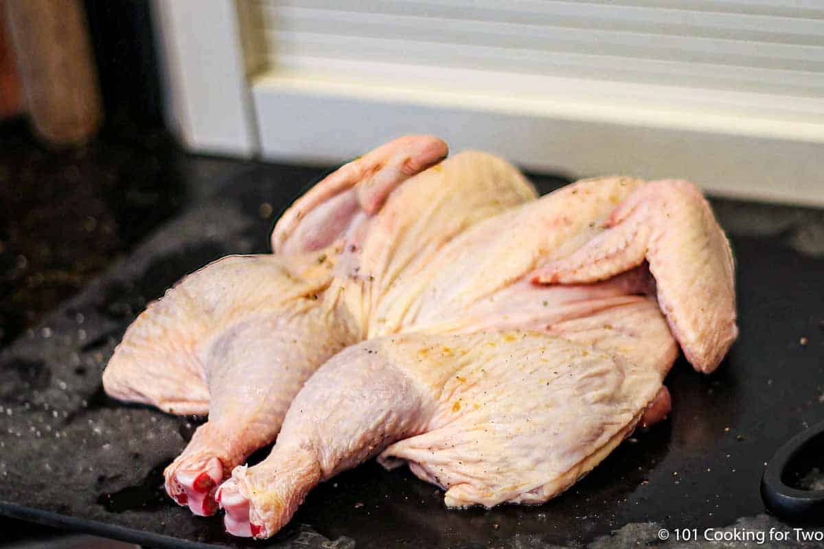 butterflied chicken on a black board