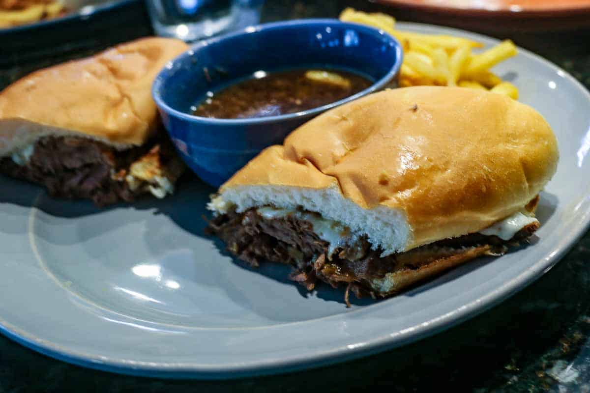 French dip sandwich with au jus on gray plate.