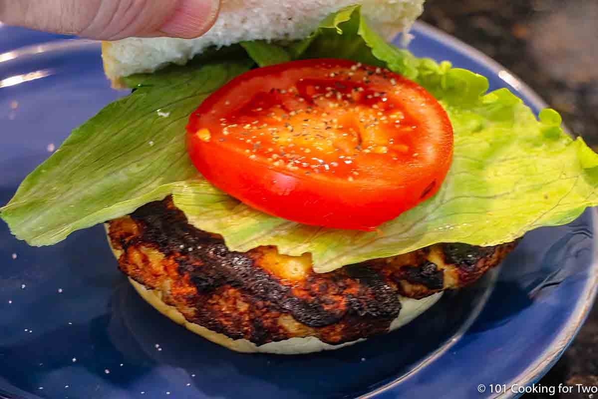 grilled chicken burger on a bun with toppings,