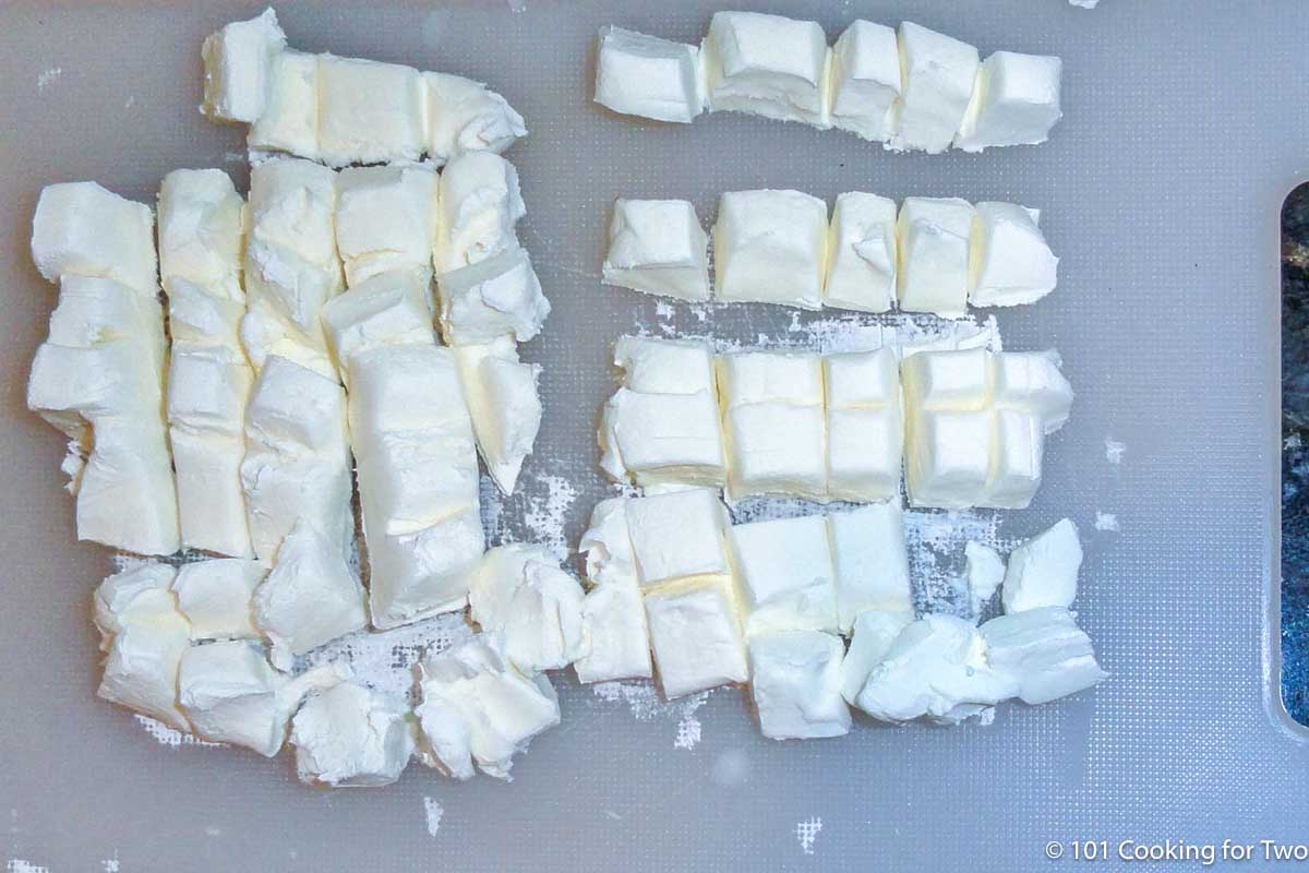 cubes of cream cheese on a cutting board.