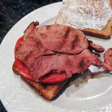 grilled ham steak on a sandwich with a tomato slice.