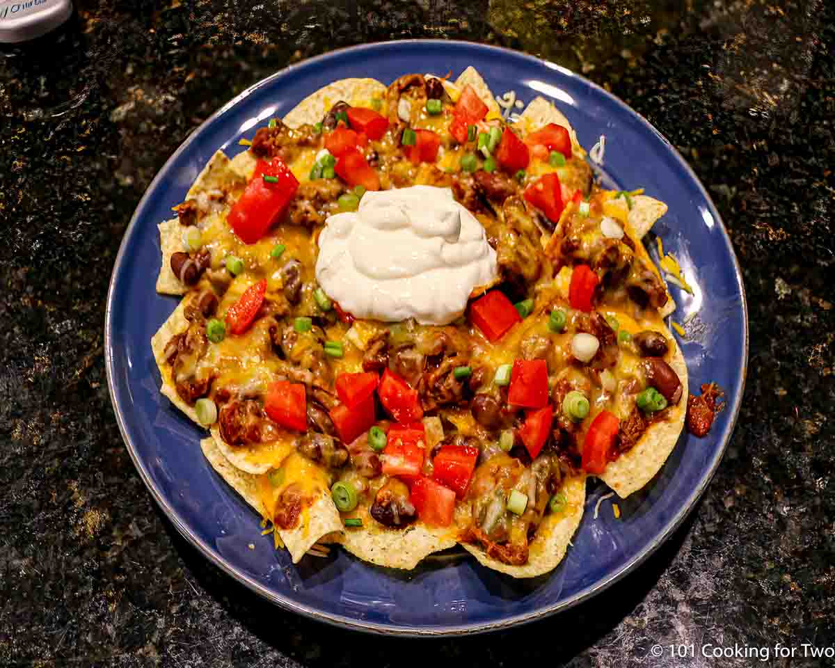 plate of cheese chili nachos with toppings.
