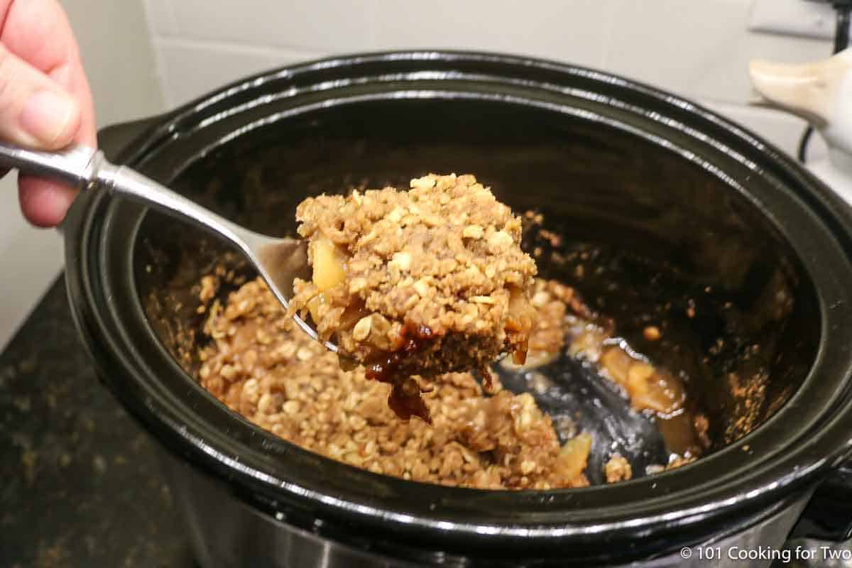 apple crisp on a spoon over a crock pot