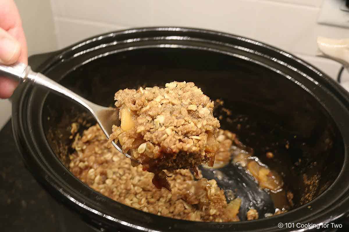 Apple crisp on a spoon over the crock pot.