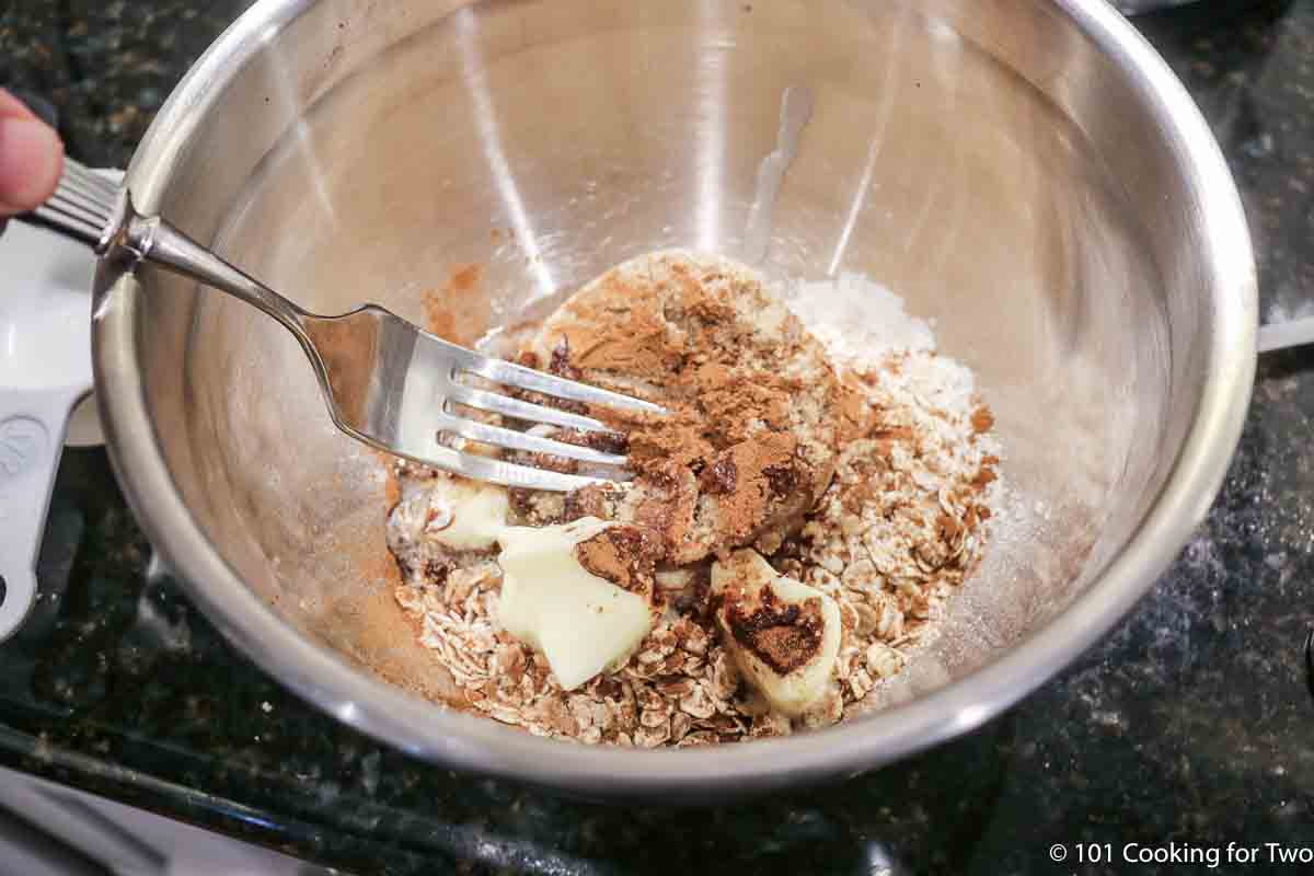 mixing topping for crisp in a metal bowl.