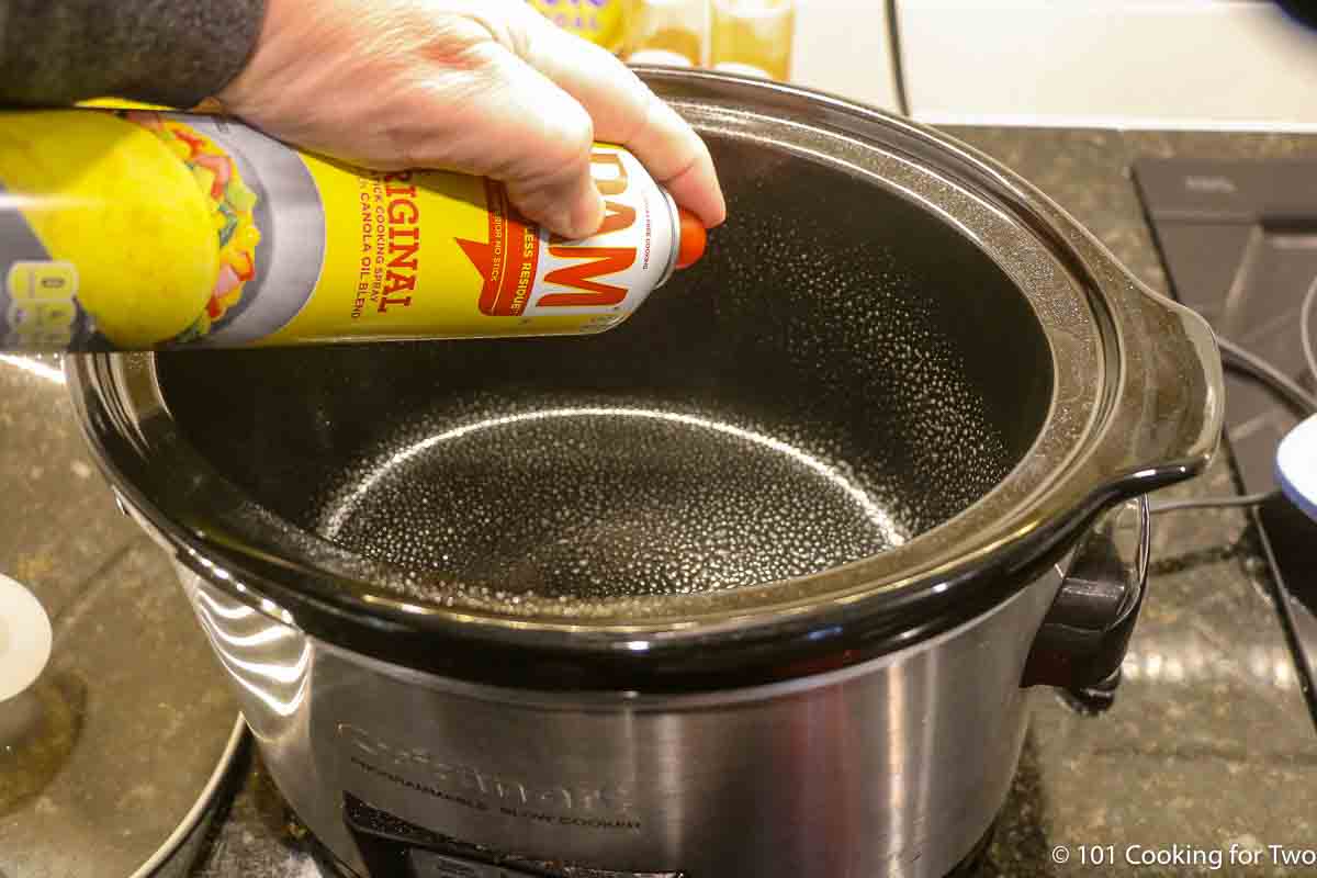 spraying a small crock pot with PAM cooking spray.