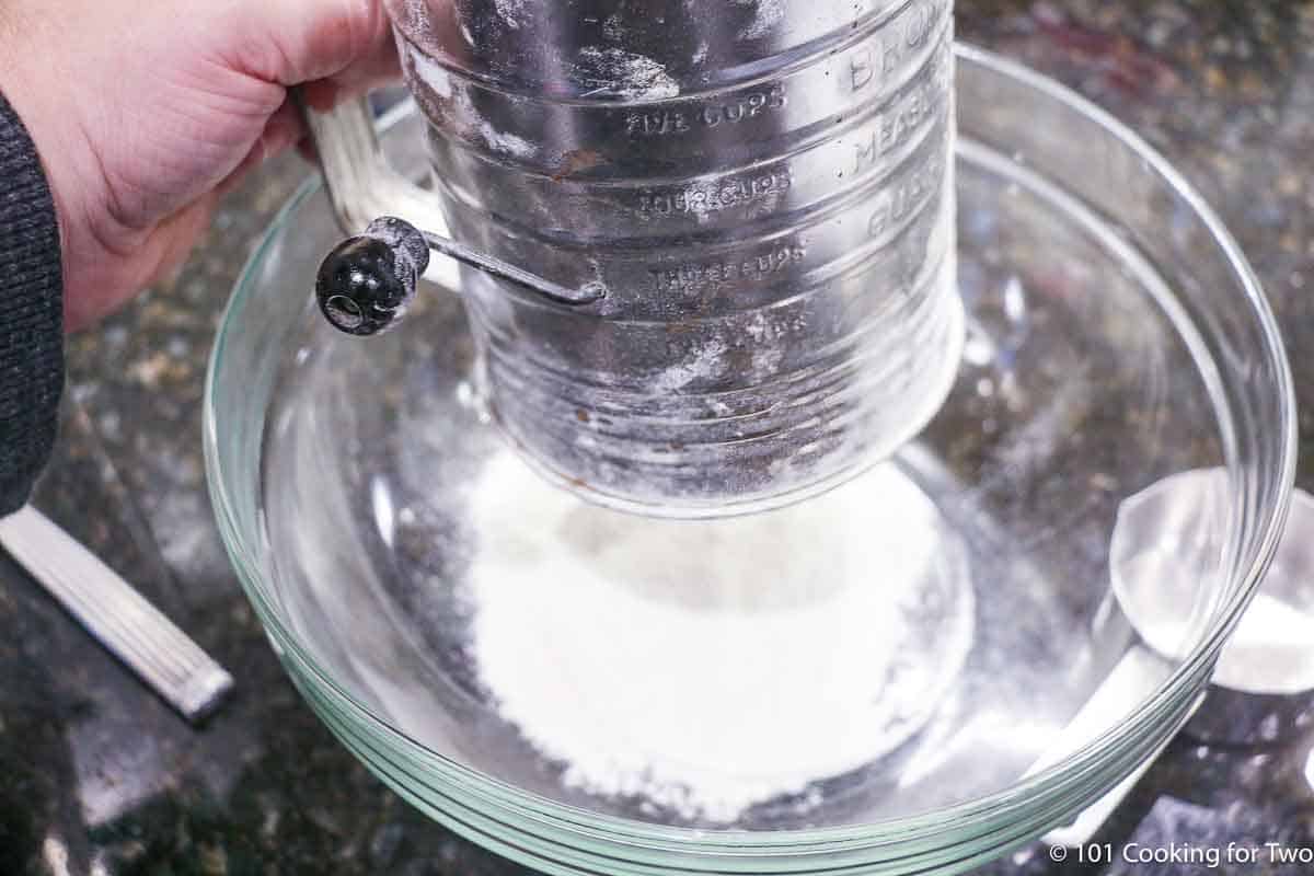 Sifting flour into glass bowl.