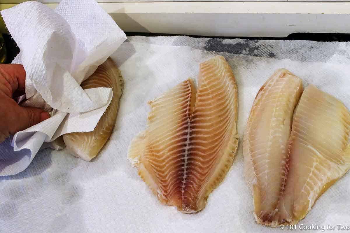 Drying tilapia filets with paper towels.