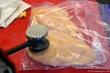 flattening chicken breasts in a bag with a meat mallet.