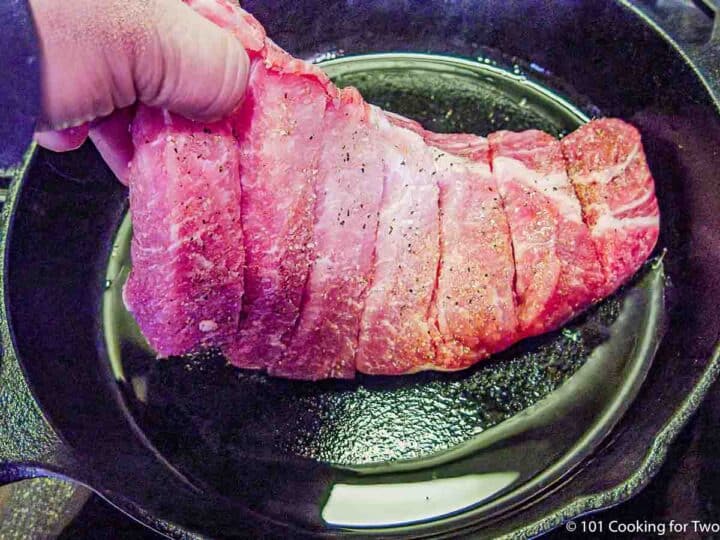 placing boneless ribs in cast iron skillet.