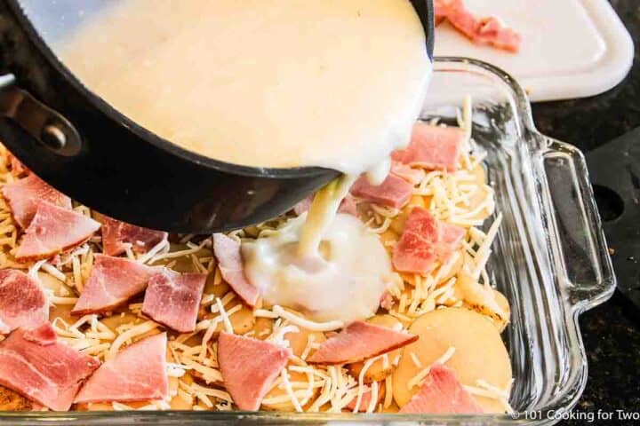 pouring sauce over layer of casserole.