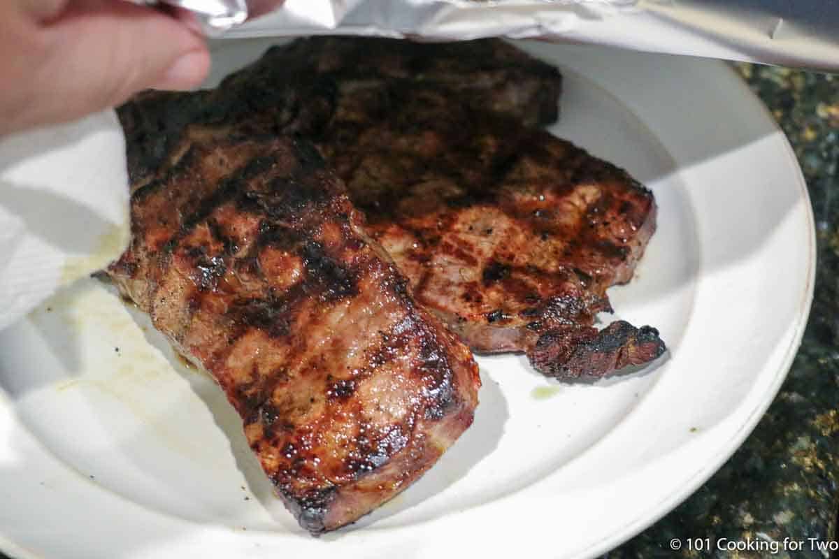 tenting cooked ribeyes with foil.