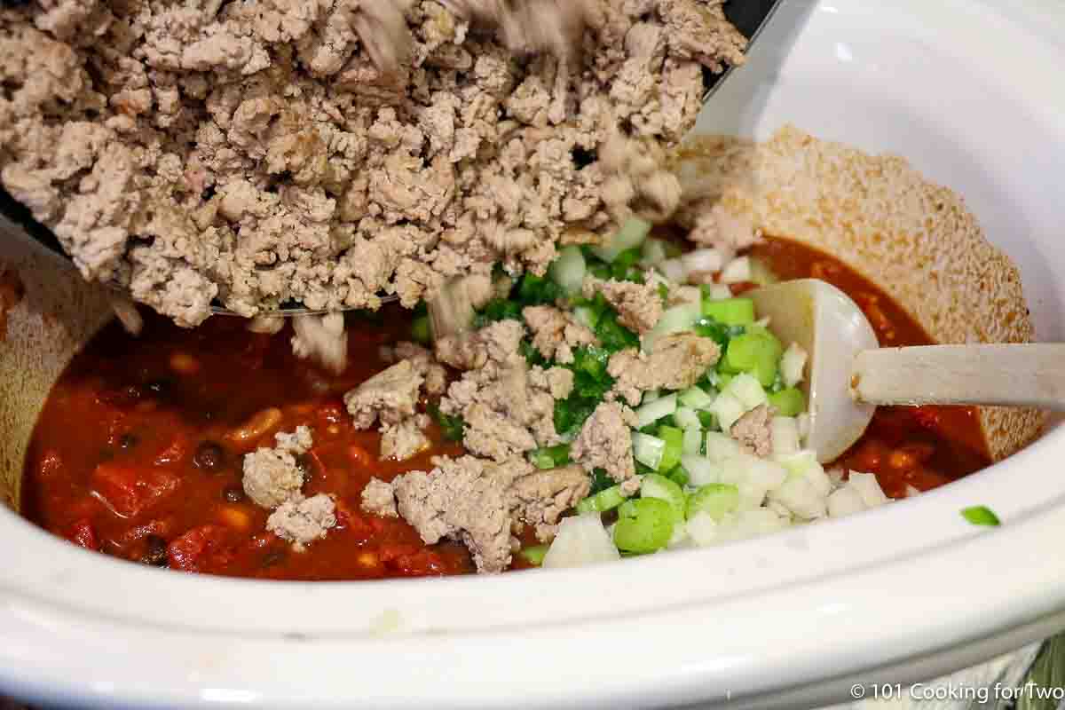 pouring browned ground meat into crock pot.