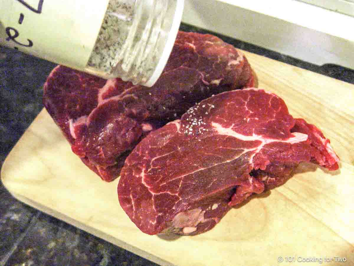 seasoning filets on a wooden board.