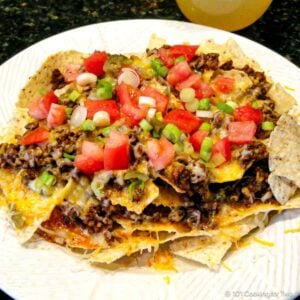 Ground beef nachos with cheese, tomatoes ,and onion.