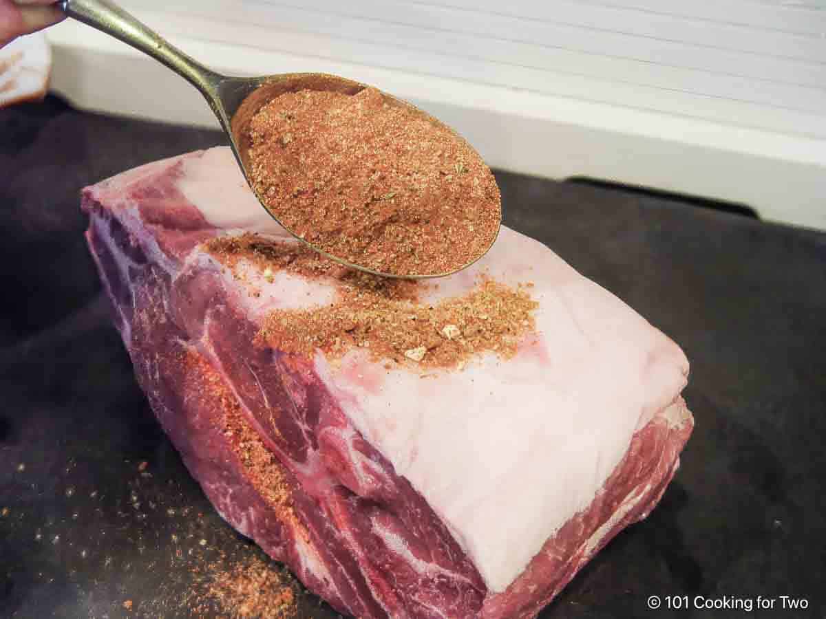 applying rub to pork butt.