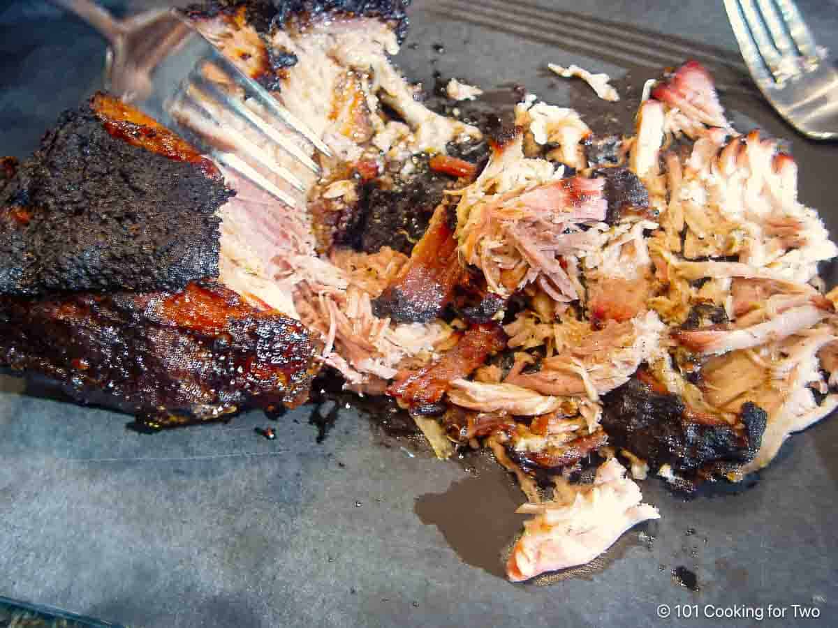 shredding cooked pork butt with forks.