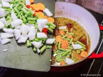 Adding vegetables to the soup.