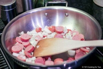 Cooking smoked sausage and onion in a pan.