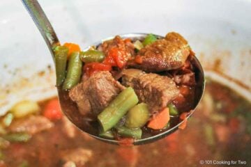 Vegetable beef soup in a ladle.