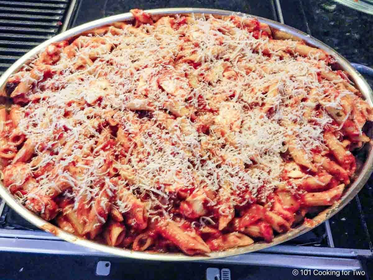Raw casserole with shredded Parmesan cheese.