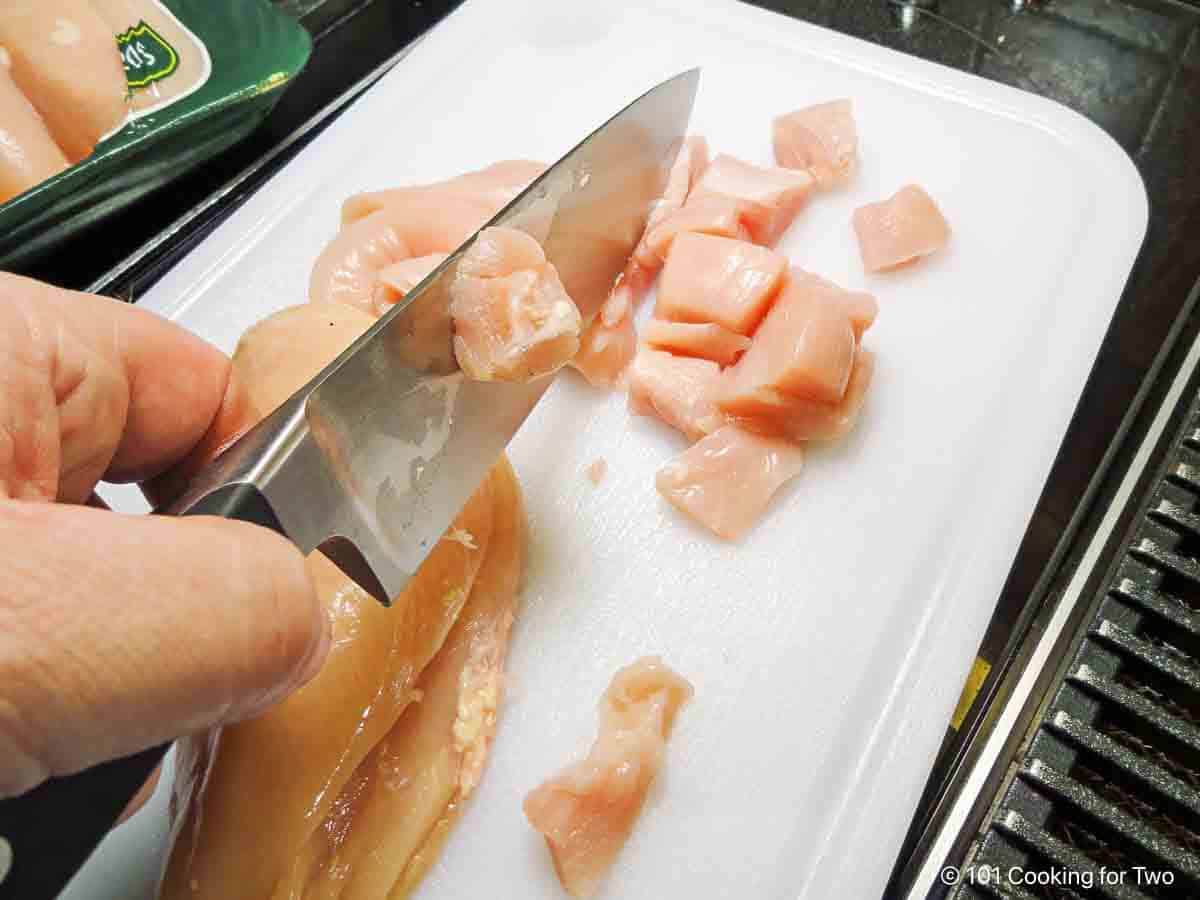 Trimming chicken into cubes.