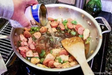 Adding broth to the cooked ingredients.