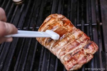 Brushing boneless ribs with BBQ sauce.