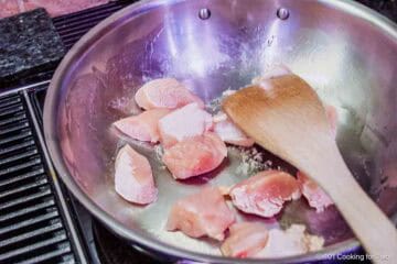 Cooking chicken cubes in a skillet.
