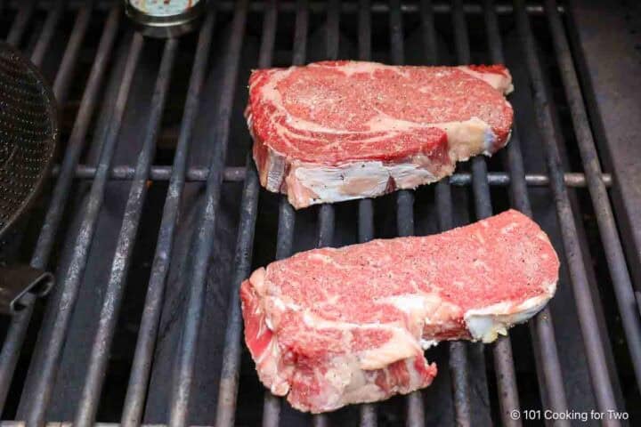 Ribeye steaks on the grill grates.