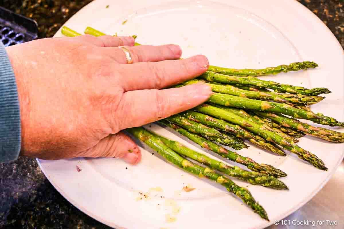 Rolling asparagus in a plate of oil and seasoning.