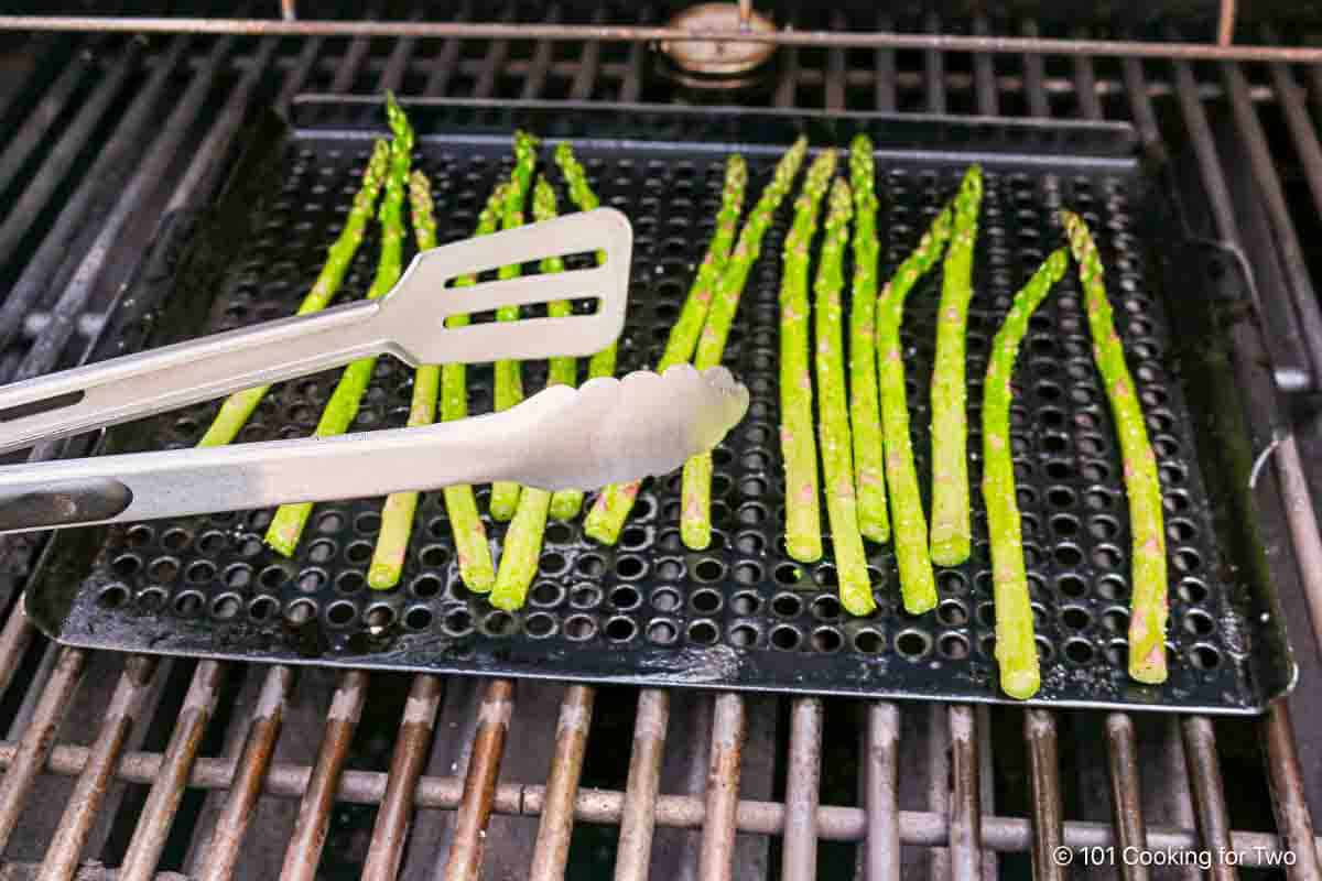 Spreading asparagus on a grill pan.