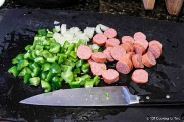 Trimming green pepper, onion and sausage.