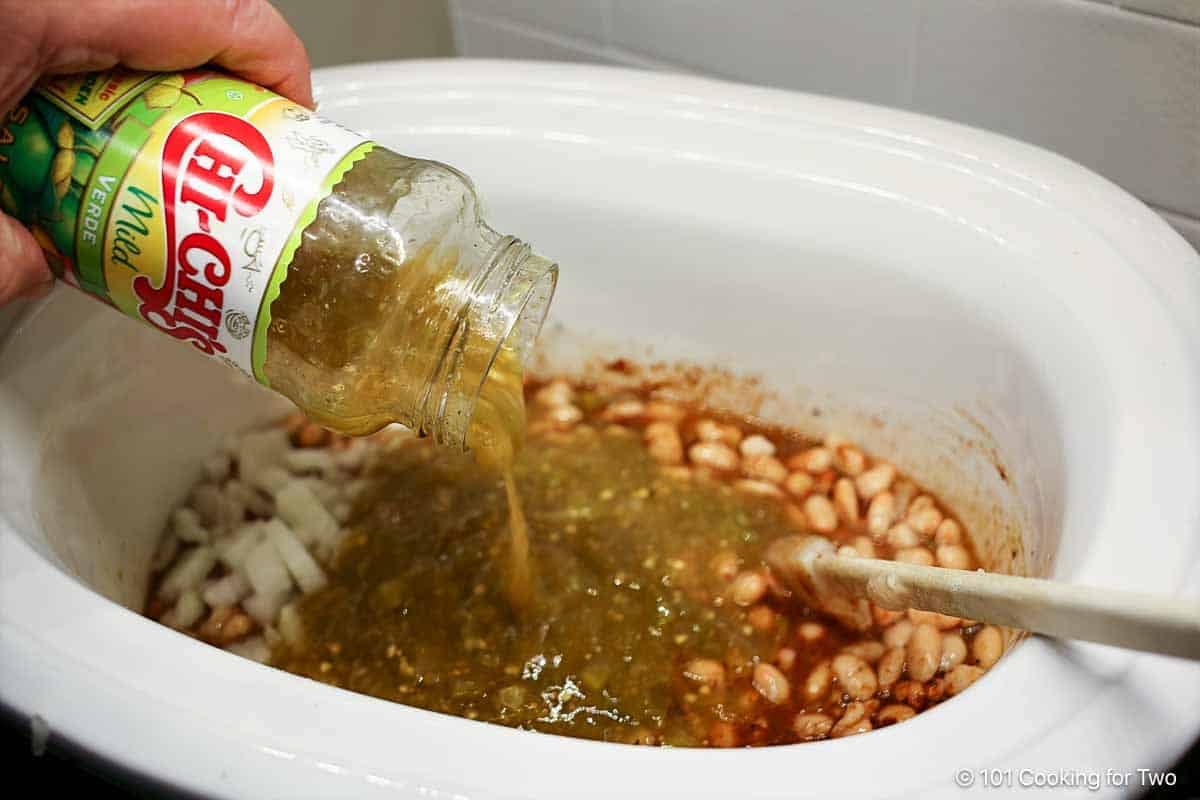 Adding salsa verde to the crock pot.